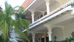 A multi-level building with a red-tiled roof, white columns, and a covered walkway. - Sueno Del Mar Resort (Roatan)