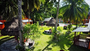 Un resort tropical con cabañas de techo de paja, palmeras y un césped bien cuidado.