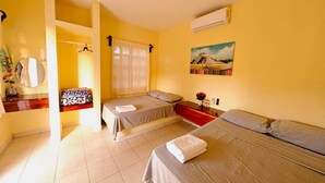 Una habitación con dos camas, un espejo, un cuadro y un equipo de aire acondicionado.