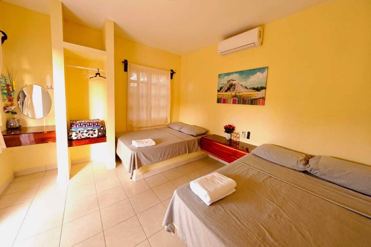 Quarto com duas camas, um espelho, um quadro e ar condicionado.