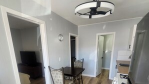A modern kitchen with a built-in stove, a dining area with a table and chairs, and a hallway leading to a bedroom. - Hat Motel (Medicine Hat)