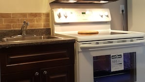A kitchen with dark wooden cabinets, a white stove, and a microwave. - Hat Motel (Medicine Hat)