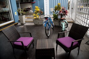 A patio area with wicker chairs and a table, a blue bicycle, and potted plants. - Andesmar (Lima)