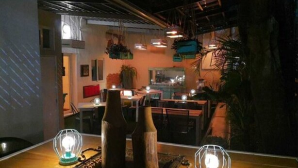 Interior de restaurante con luces colgantes, mesas y sillas de madera.
