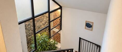 A staircase with a black railing, a wall-mounted light fixture, and a framed picture.