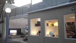 Un edificio moderno con ventanas amplias, un balcón y luces colgantes.