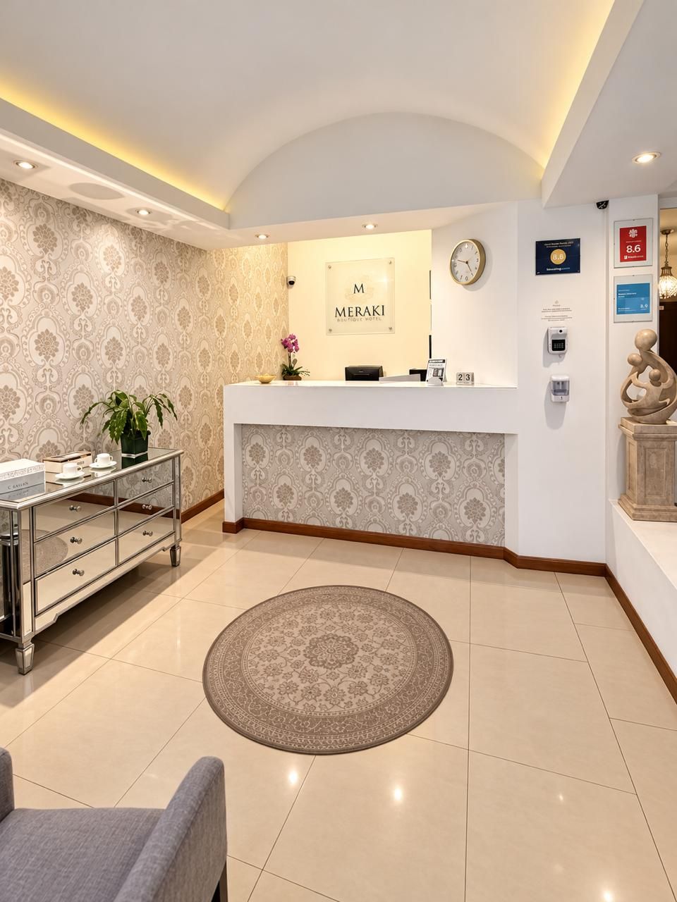 A reception area with a reception desk, a clock, a plant, a digital display, and a reception cart.