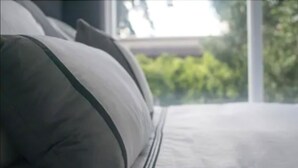 Una cama con un colchón blanco y almohadas grises.