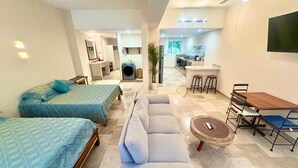 A modern hotel room with two beds, a sofa, a dining table, and a TV. - Casa del Sol (Santa María Huatulco)