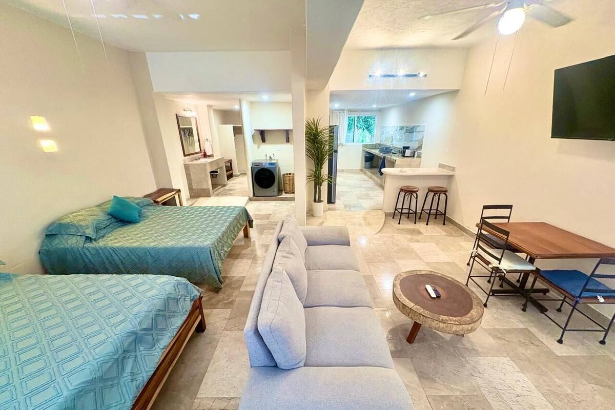 Quarto de hotel moderno com duas camas, um sofá, uma mesa de jantar e uma TV.