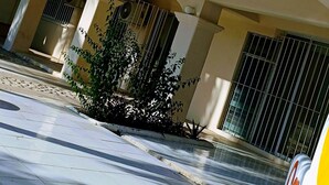 A building with multiple air conditioning units mounted on the exterior wall, large windows, and a tiled sidewalk. - Casa del Sol (Santa María Huatulco)