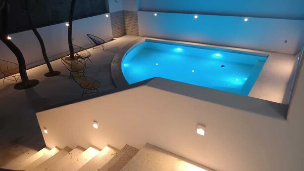 A modern outdoor pool area with a curved design, surrounded by a white wall and a staircase leading down. - Casa del Sol (Santa María Huatulco)