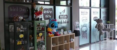 A storefront with a glass facade, shelves with various items, and a sign reading "Bird Day Boutique Hotel".