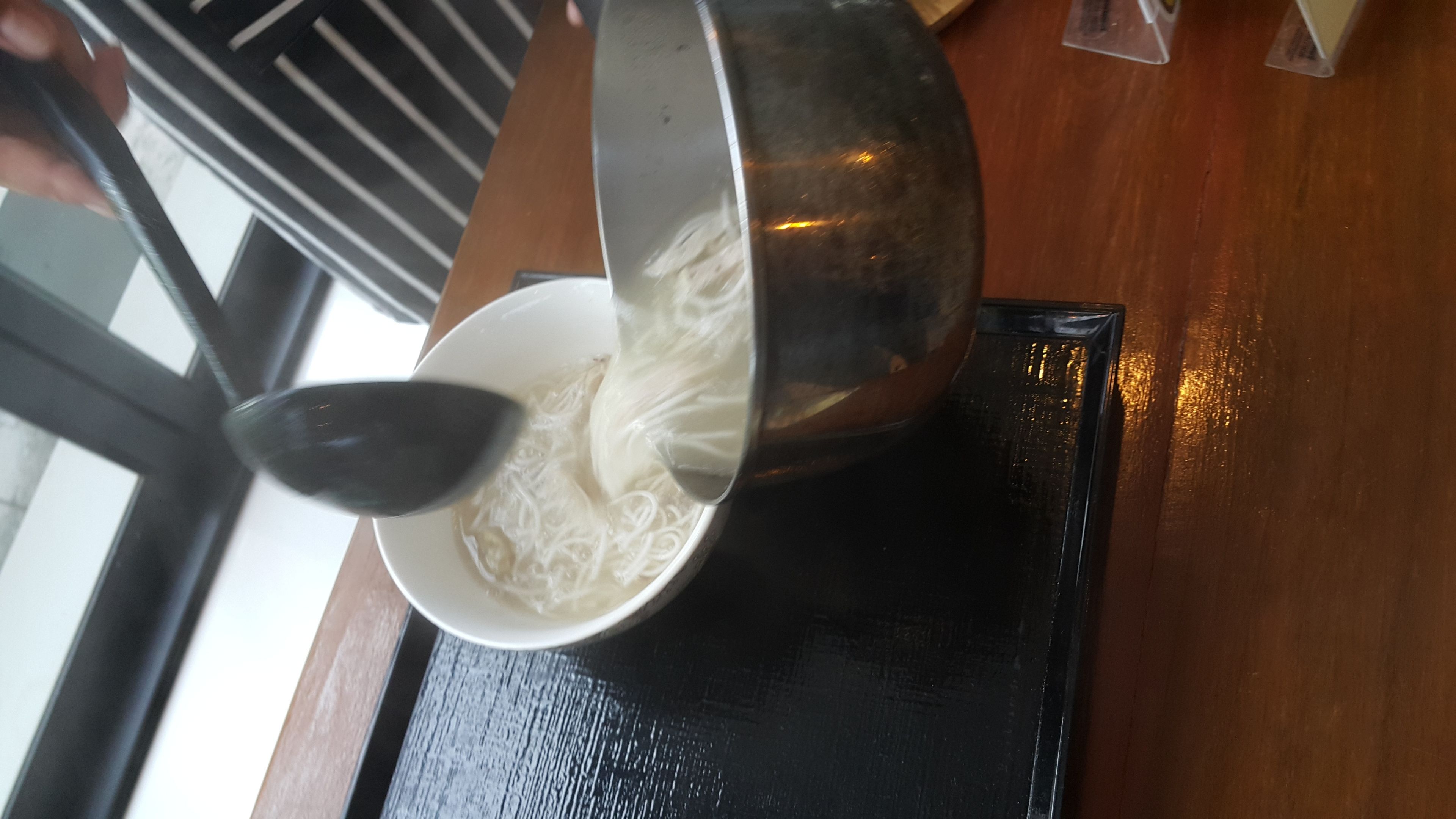 Un tazón de fideos servidos desde una olla.