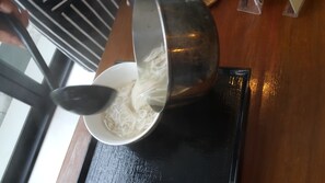 A bowl of noodles being served from a pot. - Bird Day Boutique Hotel (Mukdahan)