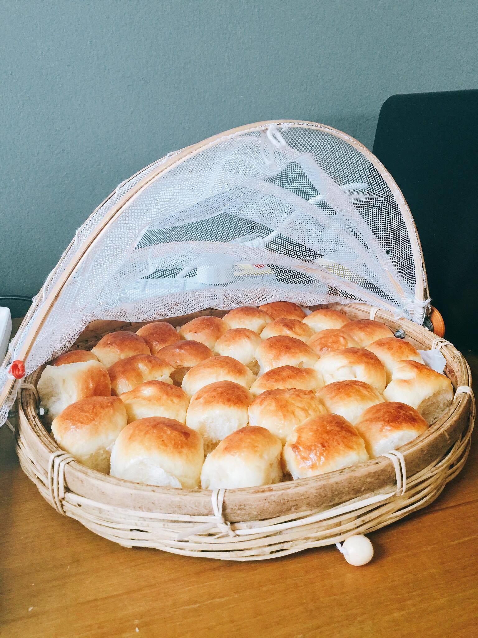 A basket of freshly baked rolls on a wooden table.
