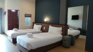 Habitación de hotel con dos camas, un espejo grande, una televisión y una maleta.