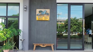 Entrada moderna de un edificio con un banco de madera, un ventanal grande y un letrero que dice 'Bird Day Boutique Hotel'.