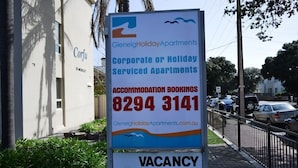 A sign for Glenelg Holiday Apartments advertising corporate or holiday serviced apartments with a contact number for accommodation bookings.