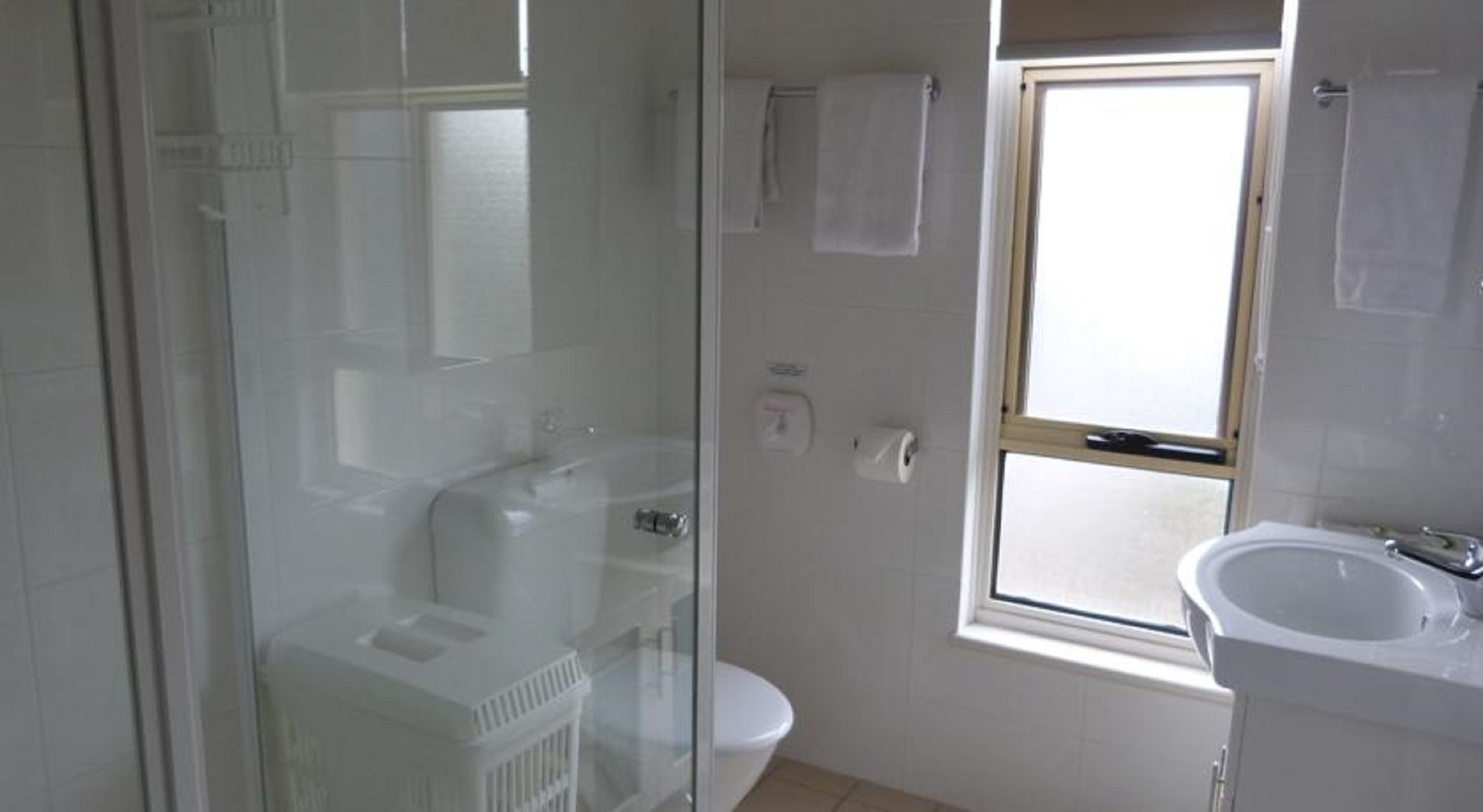 Un bagno con box doccia in vetro, un water e un lavandino.