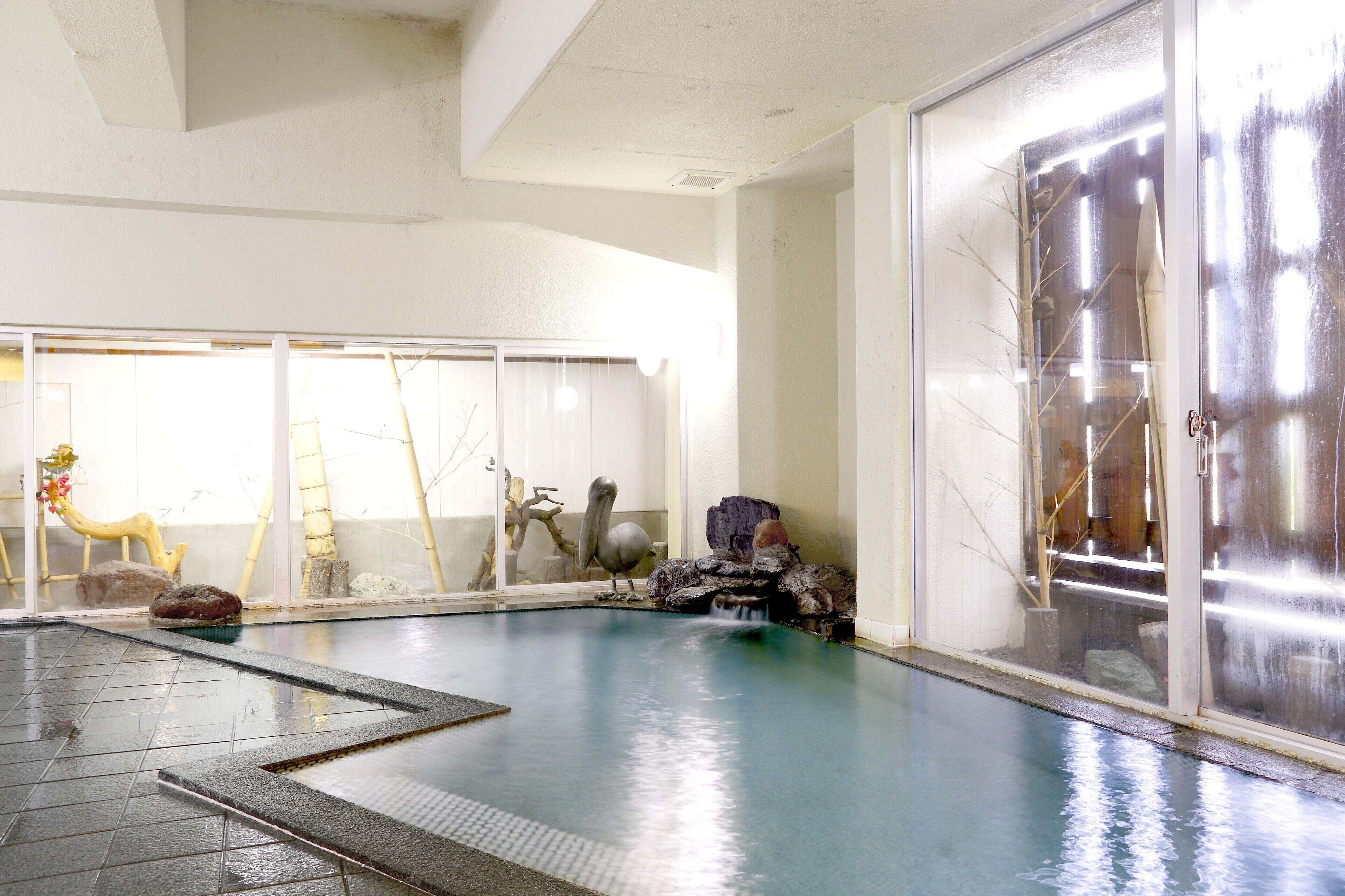 Una piscina interior con vistas despejadas del entorno, incluyendo un amplio ventanal y una escultura decorativa.