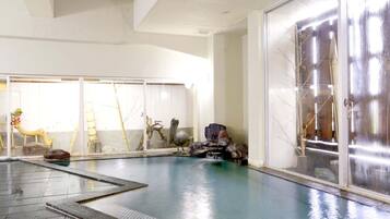 Una piscina interior con vistas despejadas del entorno, incluyendo un amplio ventanal y una escultura decorativa.