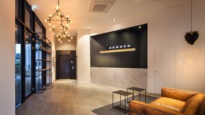 A modern lobby with a leather sofa, a chandelier, and a reception desk. - Gangneung Boutique Hotel Bombom (Gangneung)