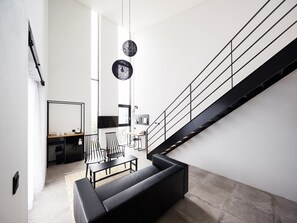 Ein modernes Wohnzimmer mit einer schwarzen Ledersofa, einem Essbereich mit Tisch und Stühlen sowie einer Treppe mit schwarzer Geländer.
