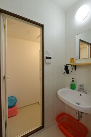 A bathroom with a white sink, a mirror, a toilet, and a shower area.