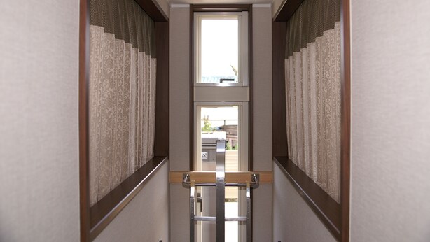 A narrow hallway with patterned curtains and a wooden handrail.