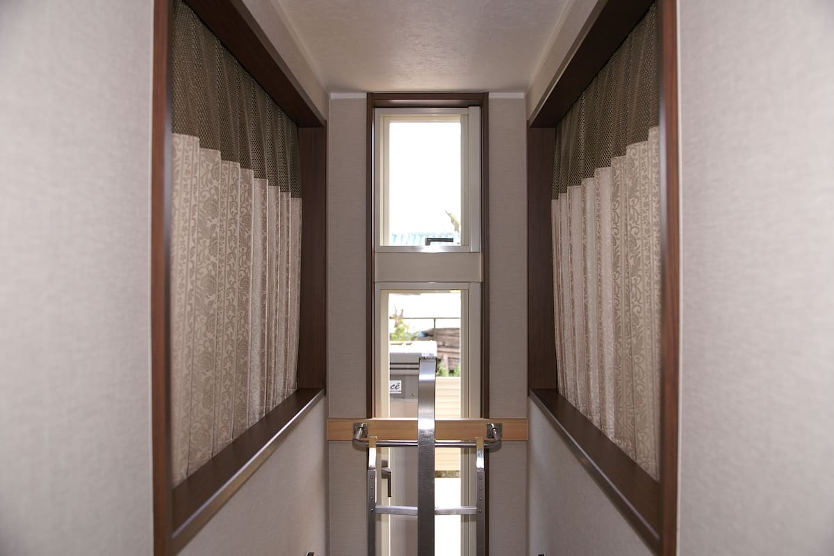 A narrow hallway with patterned curtains and a wooden handrail.