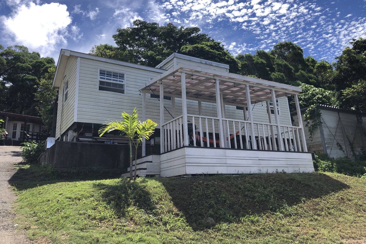 Uma casa de dois andares com varanda e um pequeno jardim.