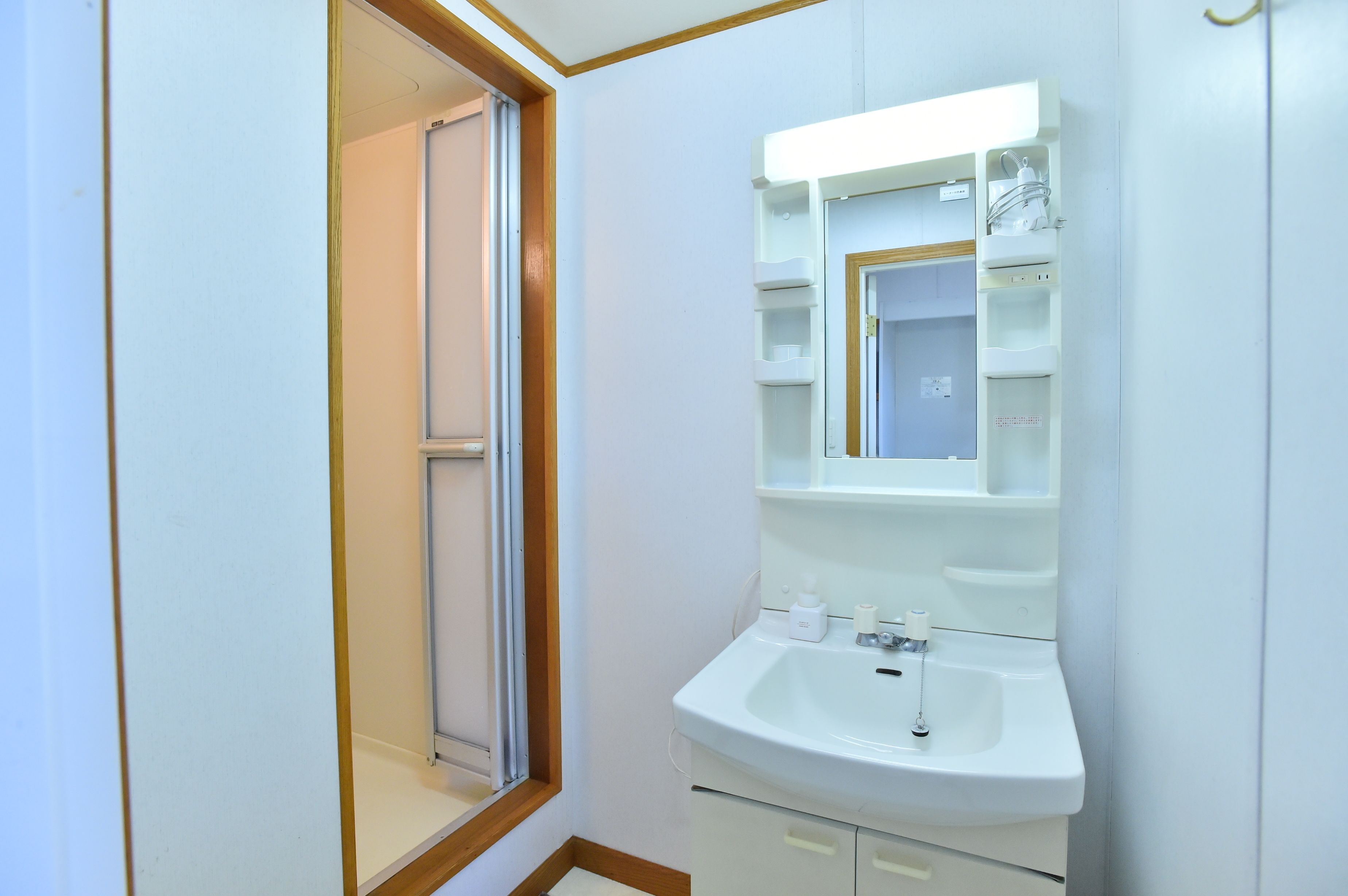 A bathroom with a white sink, mirror, and shelves.