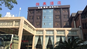 Un hotel con fachada moderna, que cuenta con un gran ventanal y un letrero con caracteres chinos.