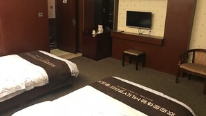 Habitación de hotel con dos camas, un escritorio, un televisor y una silla.