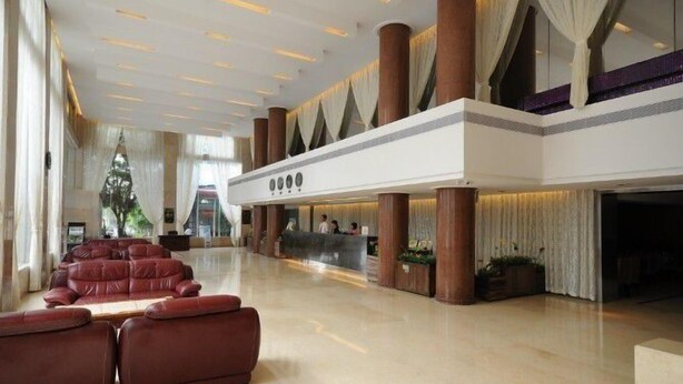 Un hallo amplio con una recepción, grandes columnas y una zona de estar con sofás rojos.