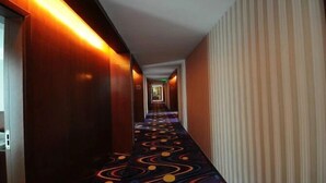 Un pasillo de hotel con alfombra estampada, paredes de madera y una pared a rayas a la derecha.