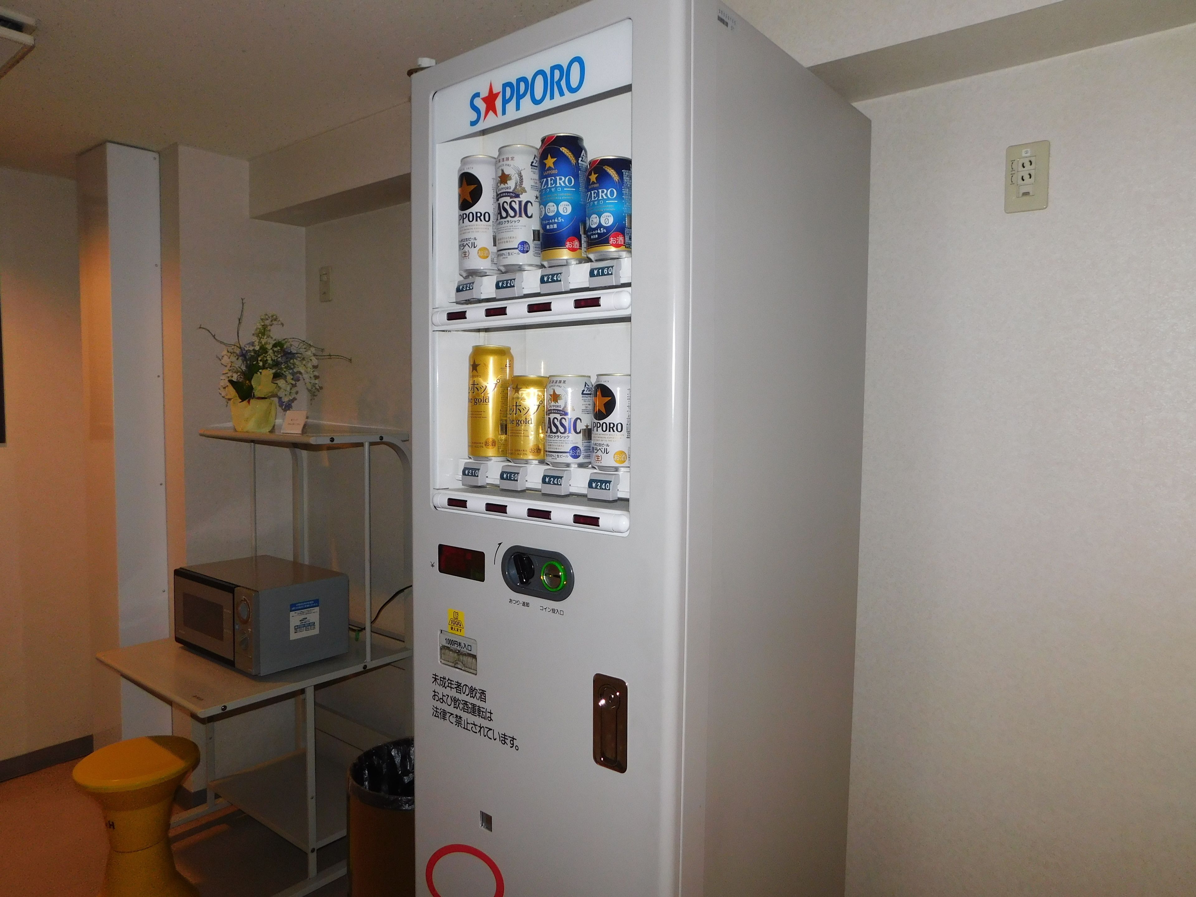 Un distributeur automatique proposant diverses boissons et un four à micro-ondes.