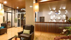 A lobby with leather chairs, a reception desk, and potted plants. - The Loft Seaside Sriracha (Si Racha)