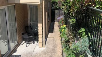 A balcony with a table and chairs, a black metal fence, and a variety of plants.