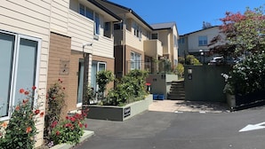 A row of townhouses with a central courtyard, each with a small garden and a visible mailbox.