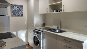 A modern kitchen with a built-in washing machine, a sink, and white cabinetry.