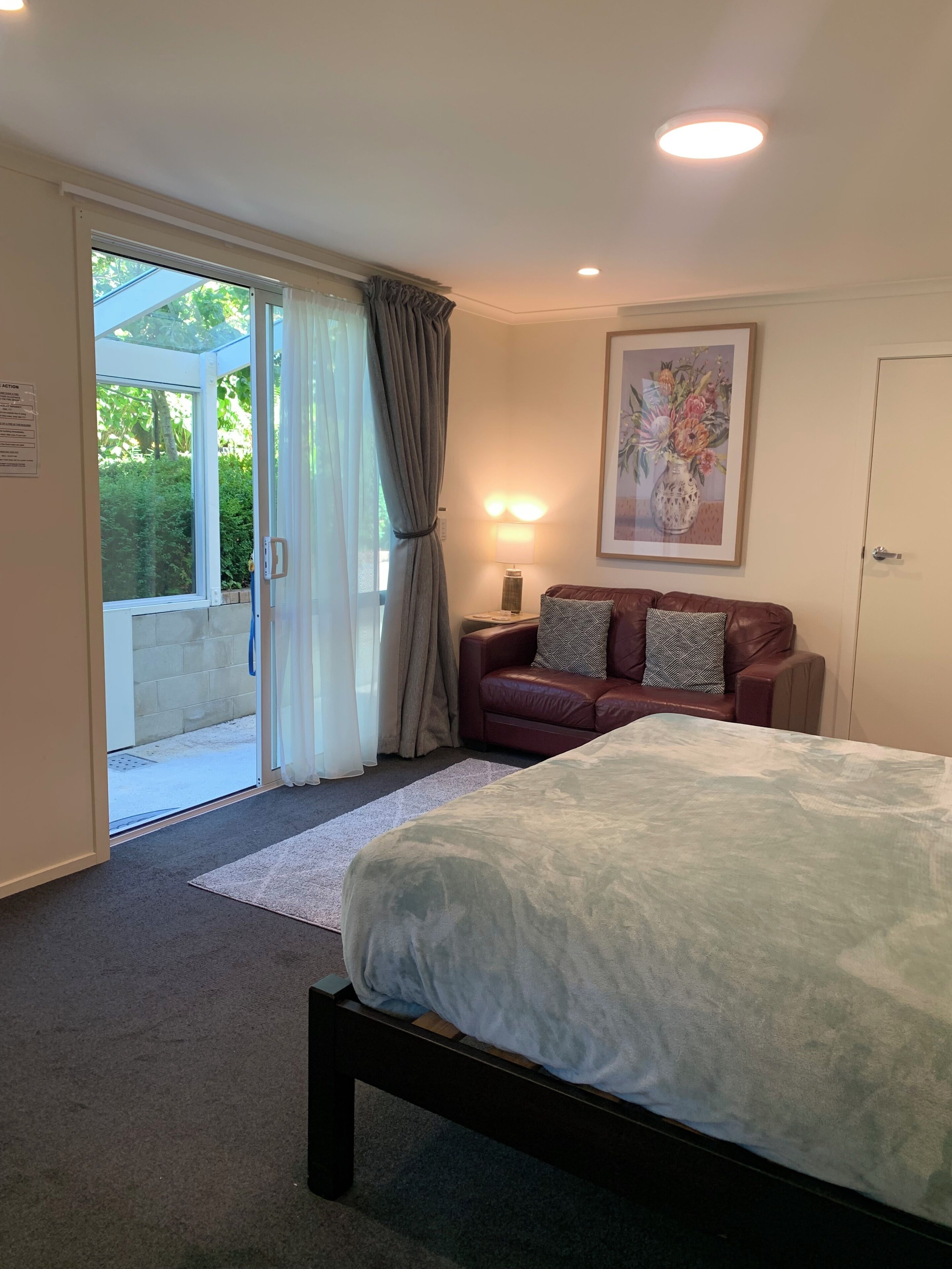 A bedroom with a bed, a sofa, a lamp, and a door.