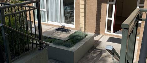 A residential building with a front entrance, a small garden area with a concrete planter, and a metal gate.