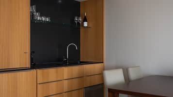 Een moderne keuken met houten kastjes, een zwart aanrecht, een geïntegreerde vaatwasser, en een eethoek met een tafel en stoelen.