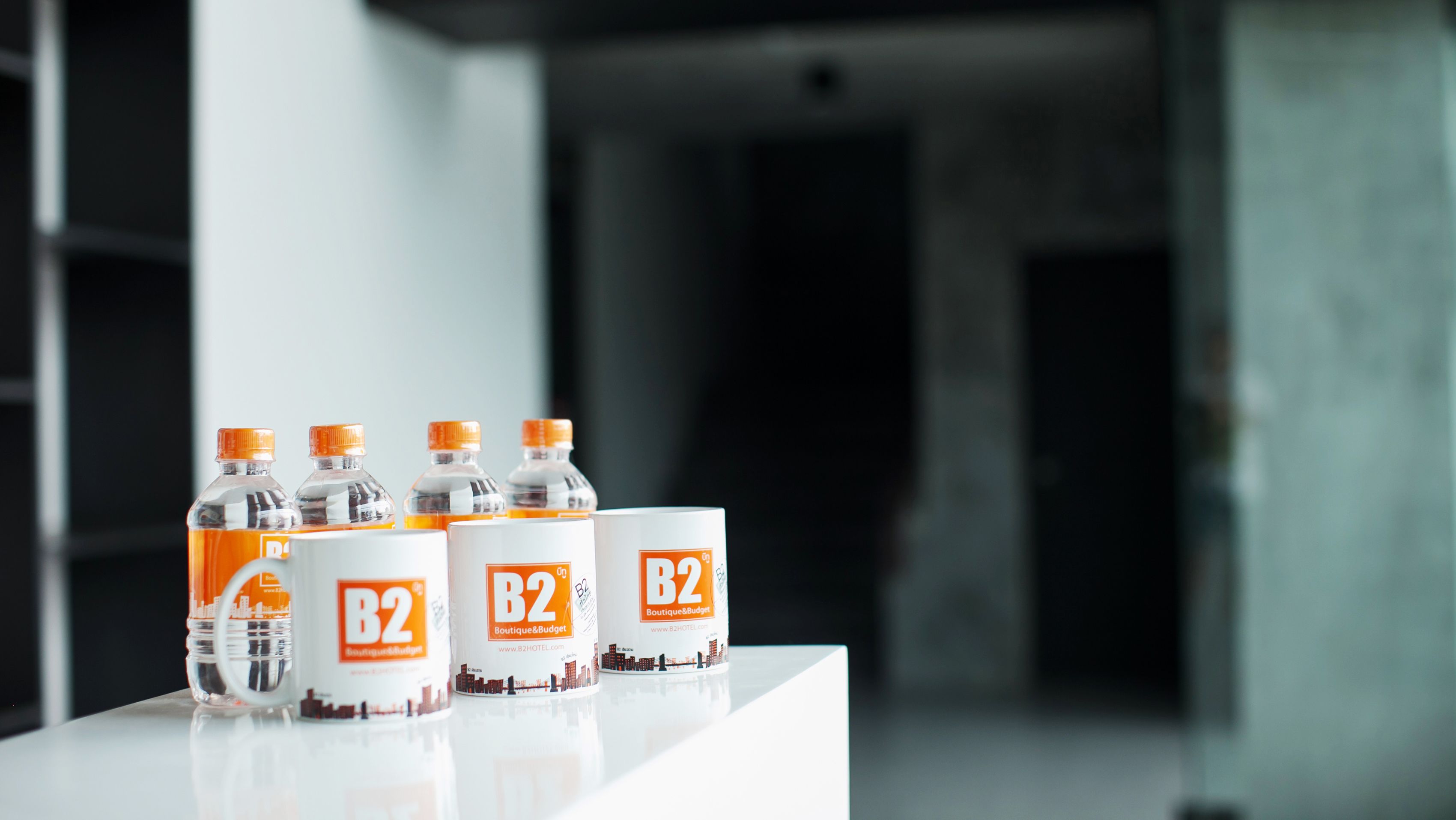 Four B2 water bottles and two B2 branded boxes on a reflective surface.