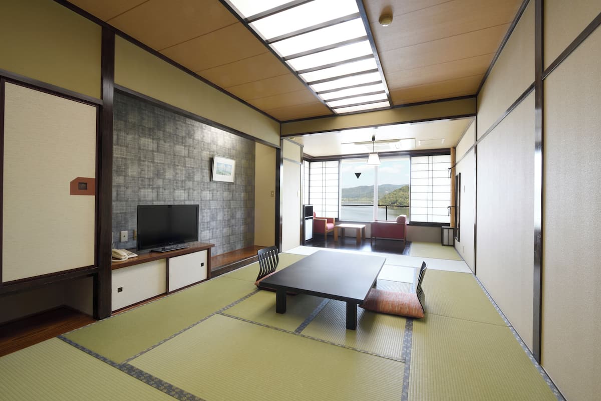 A tatami mat room with a television, a table, and a view of the outdoors.