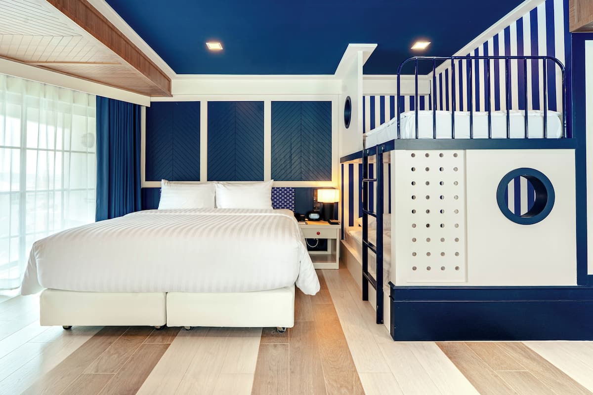 A bedroom with a bed, a nightstand, a lamp, and a bunk bed.