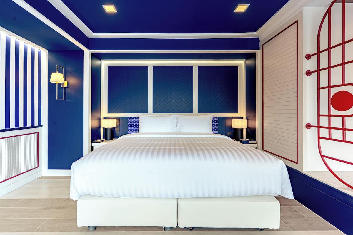 A modern bedroom with a large bed, two bedside tables, and a unique red and white wall design.