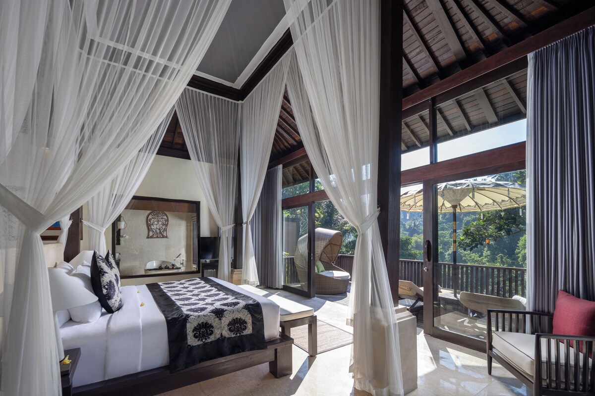 A bedroom with a bed, a balcony with a chair, and a view of the outdoors.